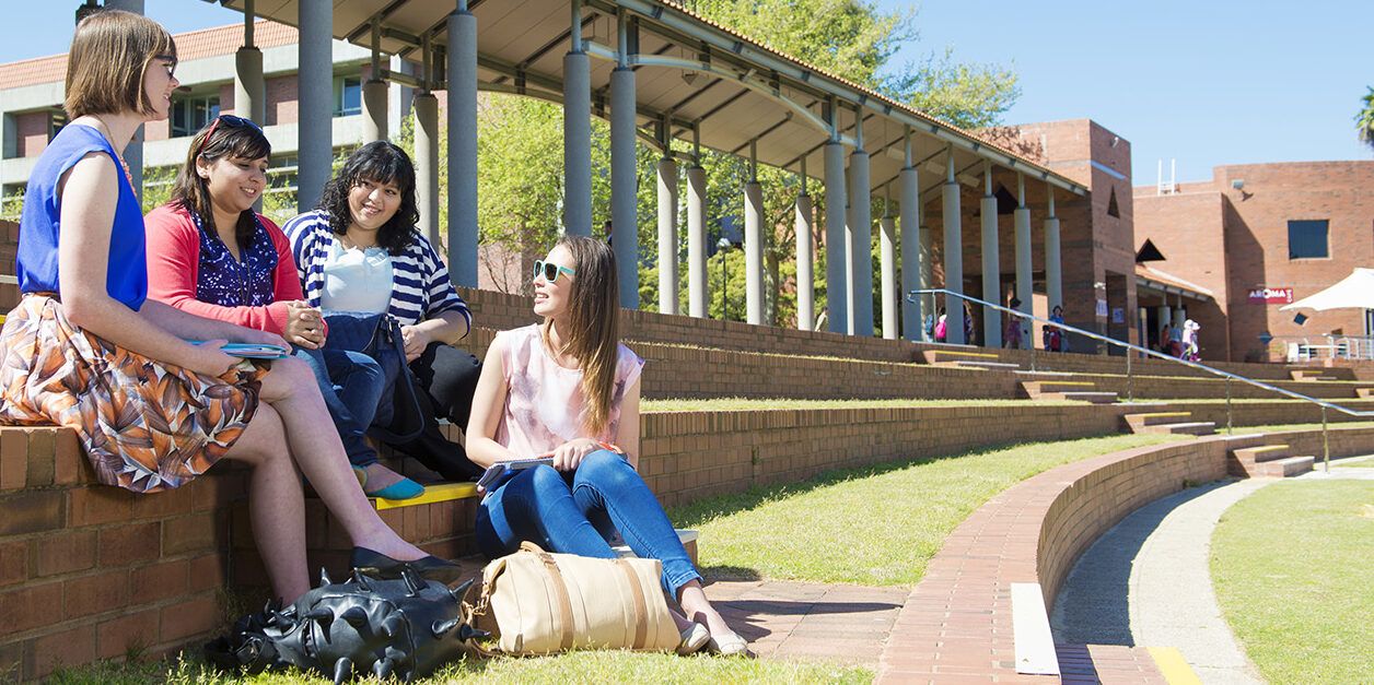 Four woman sitting on the steps on an outdoor area