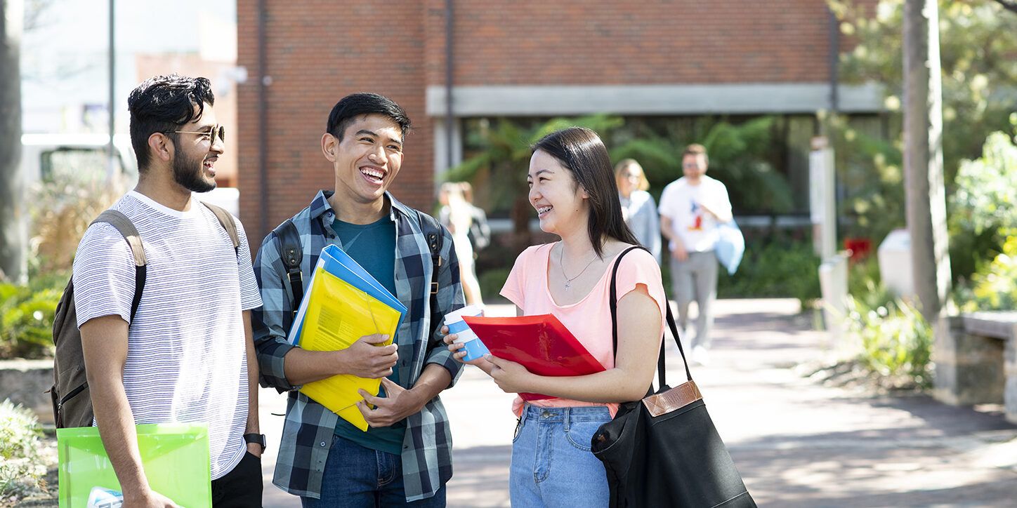 Three students holding documents standing together