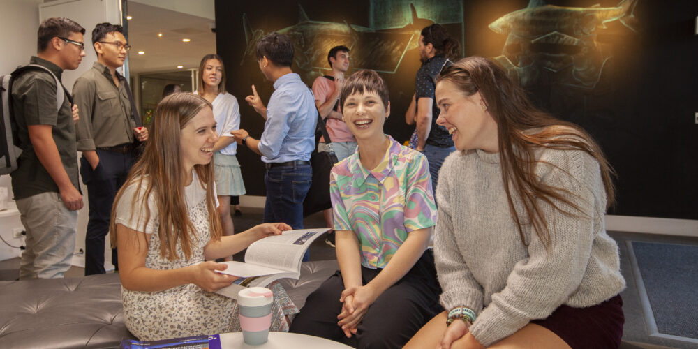 Three students sitting engaging in happy conversation