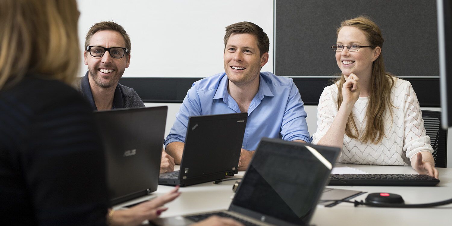 4 people gathered around a table and smiling at each other