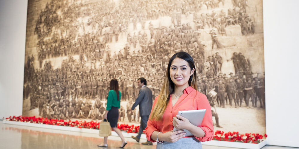 A student holding a notepad smiles at the camera